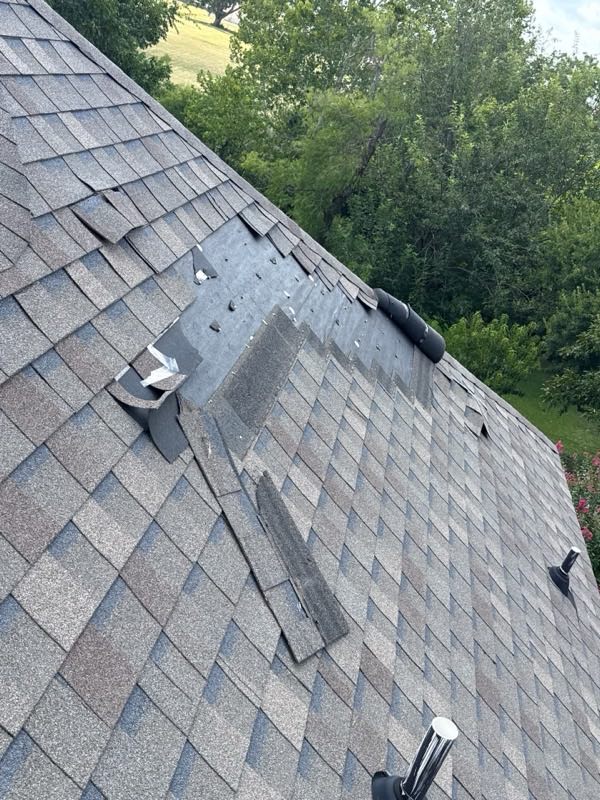 Torn shingles and an earlier patch on the same slope