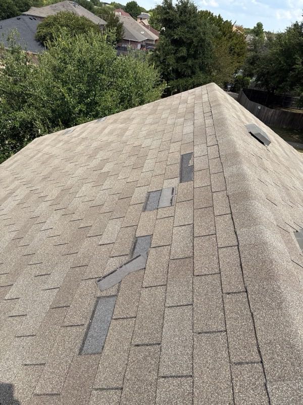 Shingle tabs lifted and displaced along a ridge line